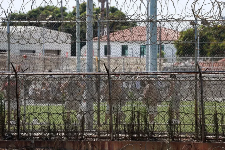 Individuals inside a prison facility behind secured gates